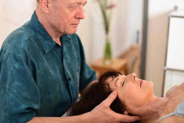 Osteopath behandelt Patientin am Kopf